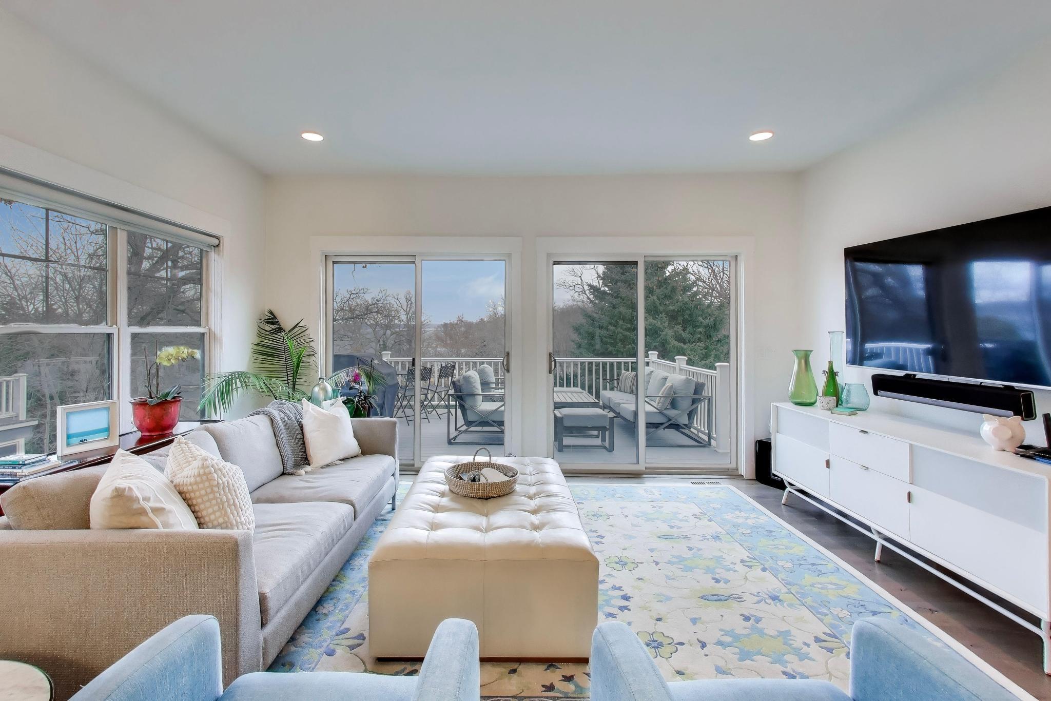 603 Agaming Road Fontana, WI 53125 - Photo 17 of 68 Sun-filled living room with expansive sliding glass doors leading to the deck, seamlessly blending indoor and outdoor living. Clean lines and modern finishes create a welcoming gathering space.