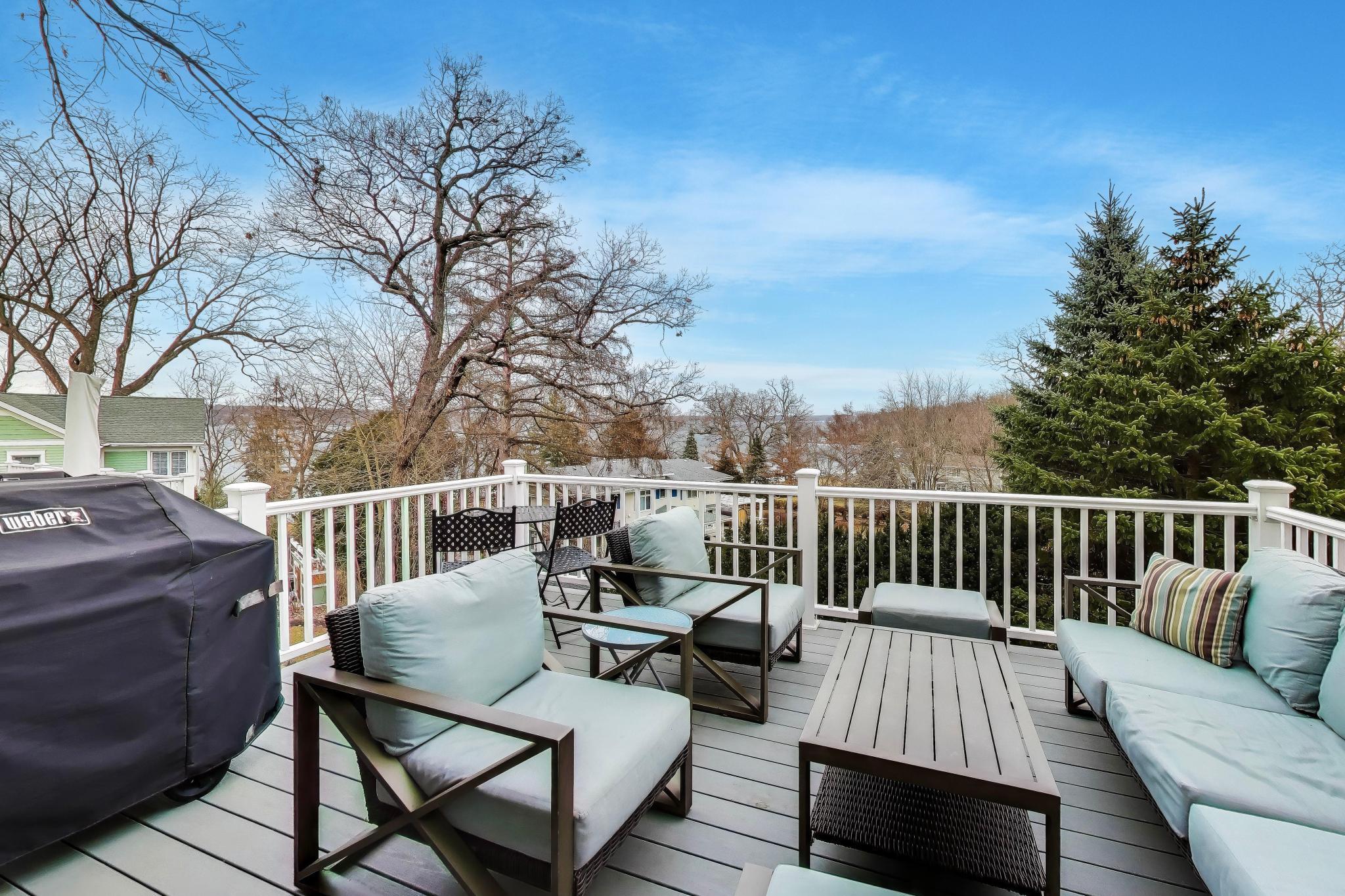 603 Agaming Road Fontana, WI 53125 - Photo 18 of 68 Elevated deck with ample seating and a grilling area, offering scenic neighborhood and water views. Perfect for outdoor dining or evening gatherings.