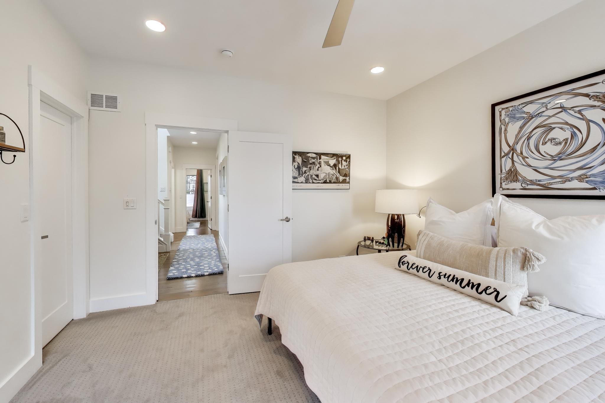 603 Agaming Road Fontana, WI 53125 - Photo 25 of 68 Comfortable main floor suite with soft carpeting, modern ceiling fan, and direct access to the private bath. A calming space designed for rest and relaxation.