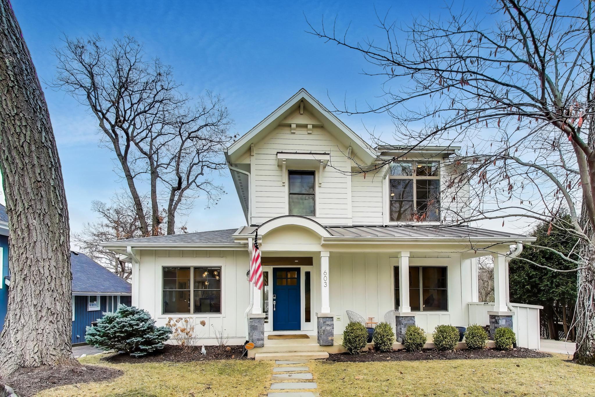 603 Agaming Road Fontana, WI 53125 - Photo 2 of 68 Charming two-story exterior with covered front porch, blue accent door, and mature trees framing the landscaped yard.