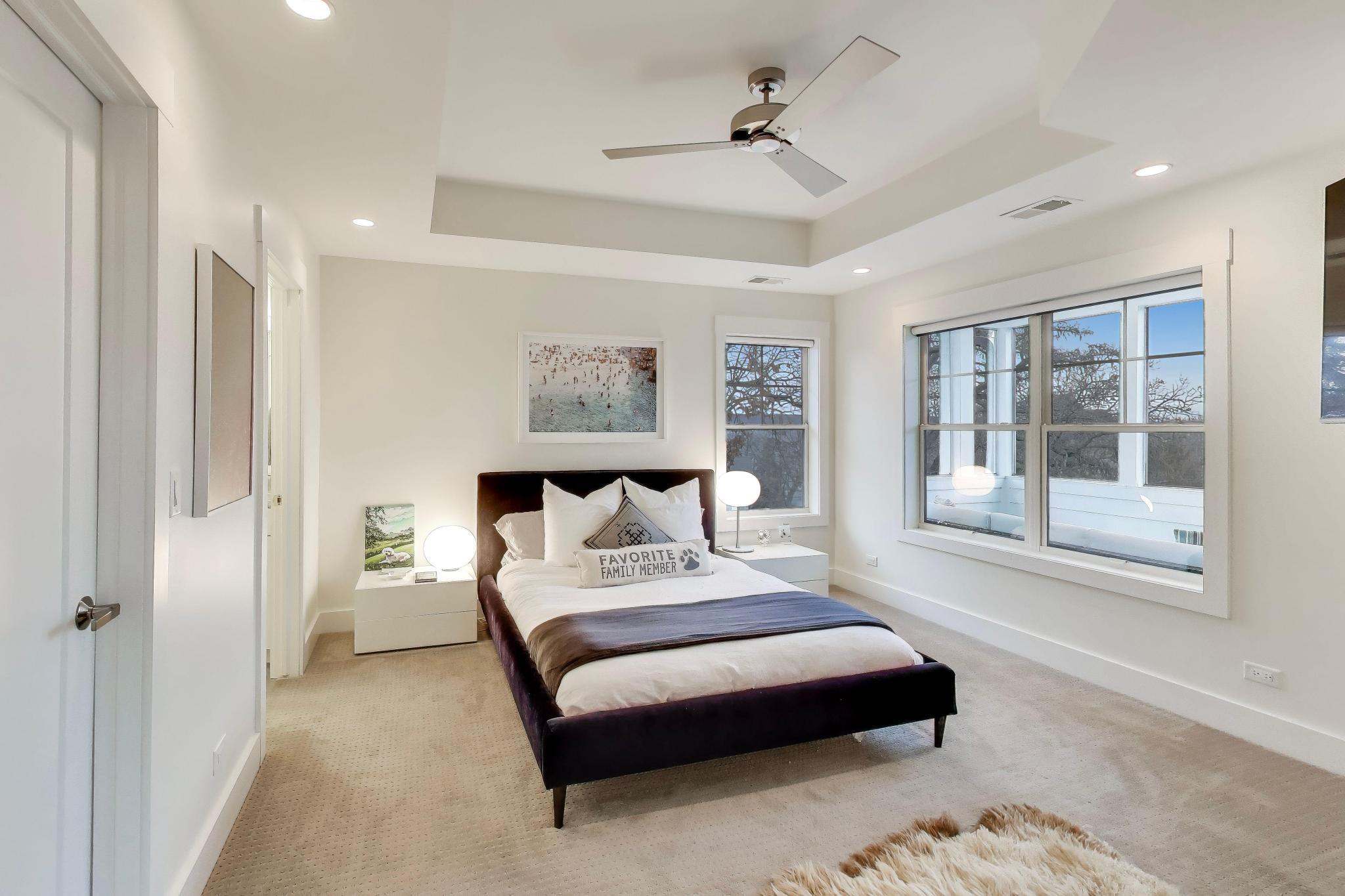 603 Agaming Road Fontana, WI 53125 - Photo 33 of 68 Spacious primary suite with tray ceiling detail, ceiling fan, and large windows that fill the room with natural light.