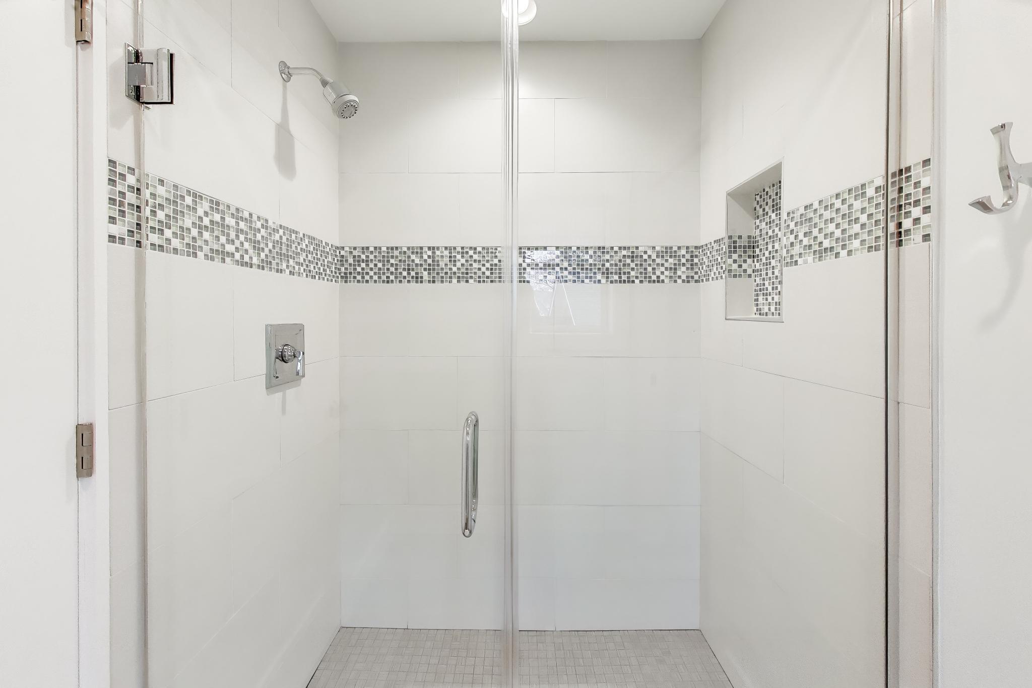 603 Agaming Road Fontana, WI 53125 - Photo 37 of 68 Glass-enclosed walk-in shower with large-format tile and decorative mosaic accent band.