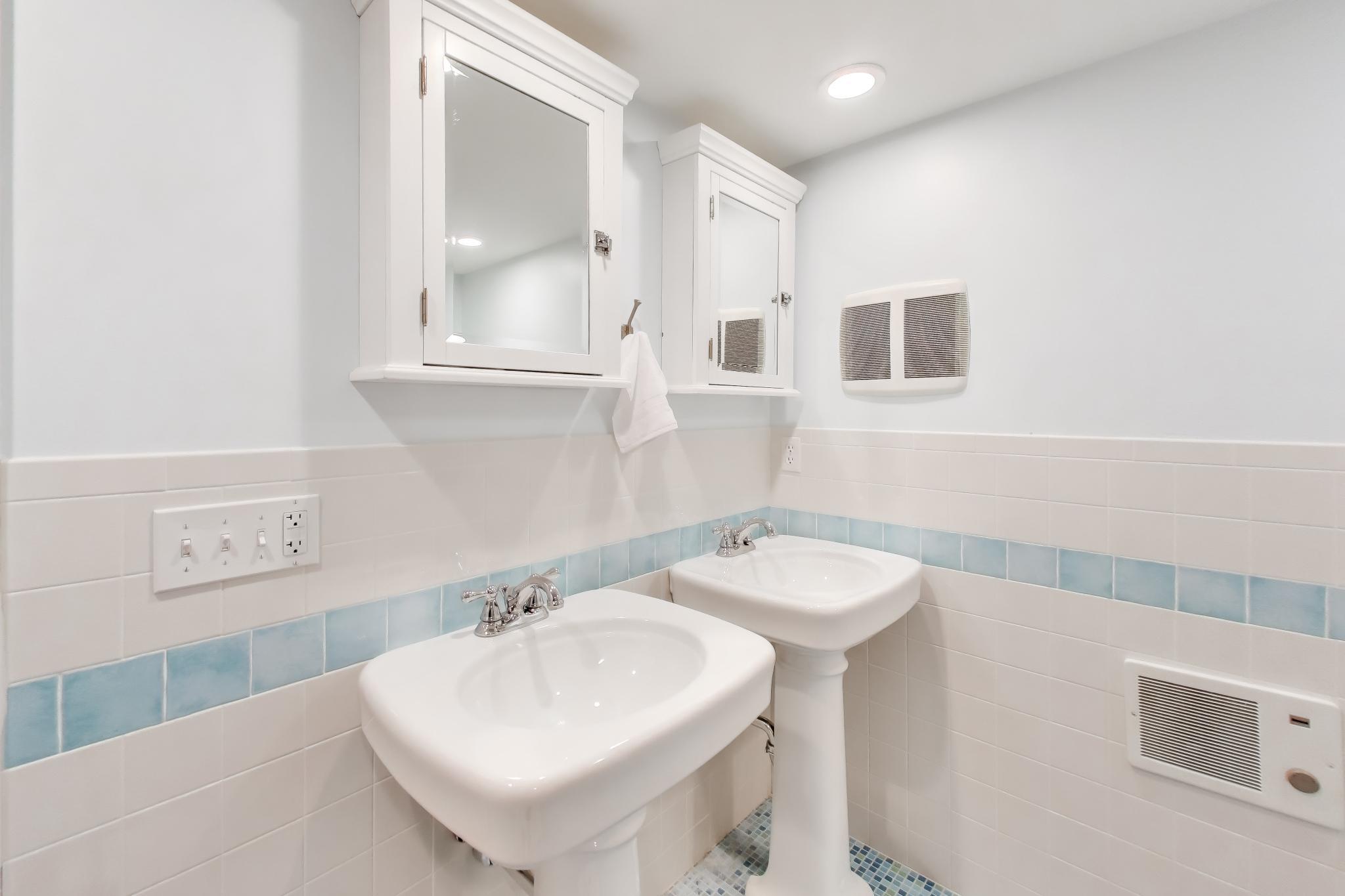 603 Agaming Road Fontana, WI 53125 - Photo 47 of 68 Charming bath featuring dual pedestal sinks, classic tilework, and built-in mirrored cabinets.