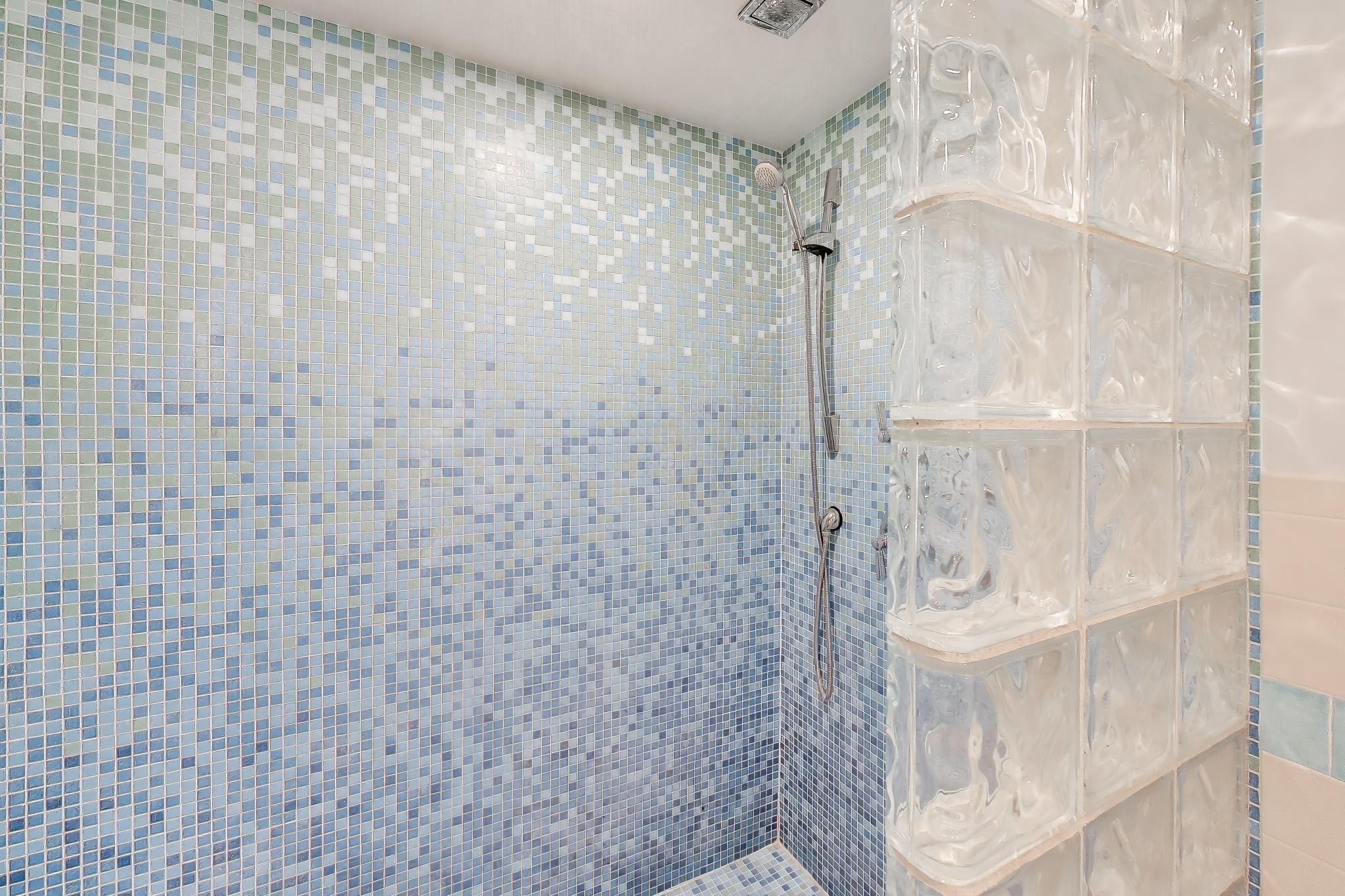 603 Agaming Road Fontana, WI 53125 - Photo 48 of 68 Contemporary bathroom featuring a walk-in shower with mosaic tile surround and glass block detailing, creating a clean and modern aesthetic.