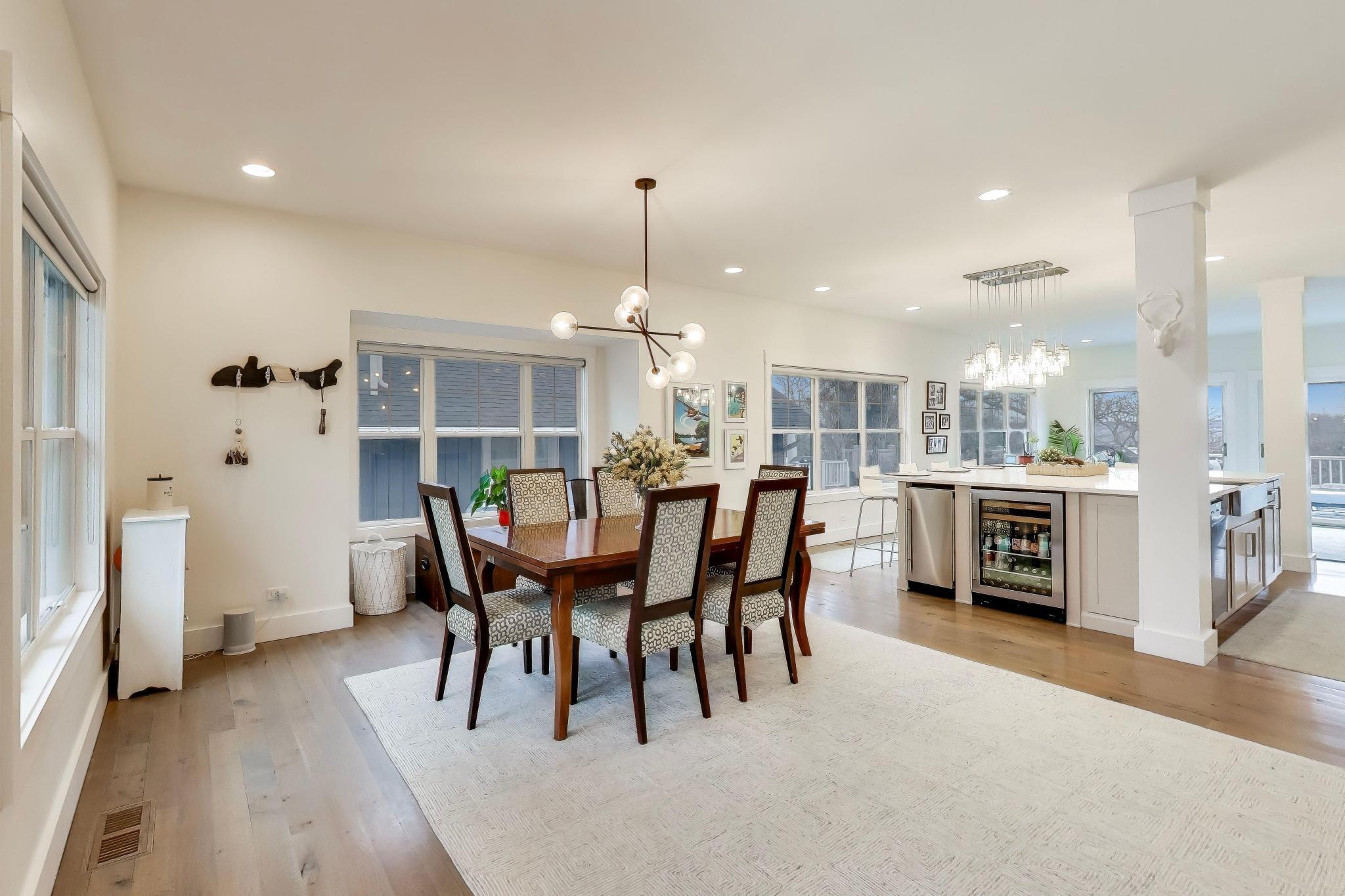 603 Agaming Road Fontana, WI 53125 - Photo 7 of 68 Seamless flow between dining and kitchen spaces, highlighted by wide-plank flooring, statement lighting, and a functional layout for entertaining.