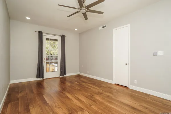 a view of an empty room with a window and wooden floor