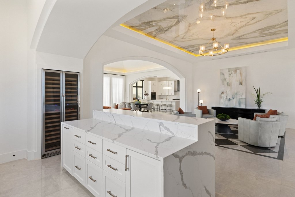 7117 Davenport Divide Road Austin, TX 78738 - Photo 28 of 40 A grand, open-concept living area features a kitchen island, wine cooler, and high ceilings with marble-look detailing.