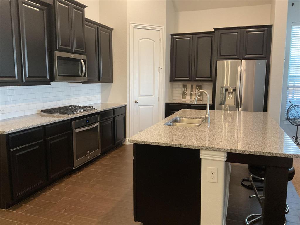 2805 Newsom Ridge Drive Mansfield, TX 76063 - Photo 8 of 33 a kitchen with kitchen island granite countertop stainless steel appliances and wooden cabinets