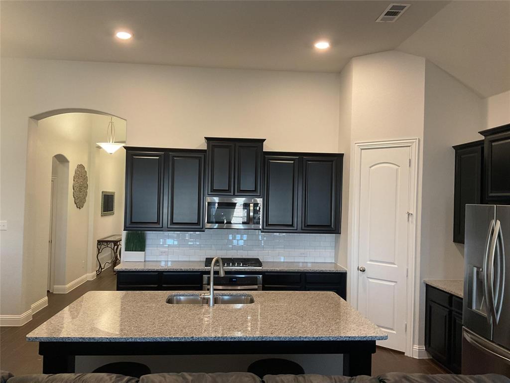 2805 Newsom Ridge Drive Mansfield, TX 76063 - Photo 9 of 33 a kitchen with stainless steel appliances a sink a refrigerator and wooden cabinets