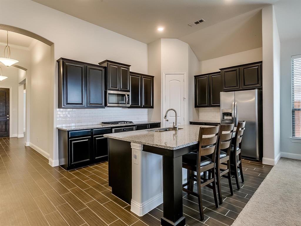 2805 Newsom Ridge Drive Mansfield, TX 76063 - Photo 10 of 33 a kitchen with stainless steel appliances kitchen island granite countertop a stove a sink and a microwave