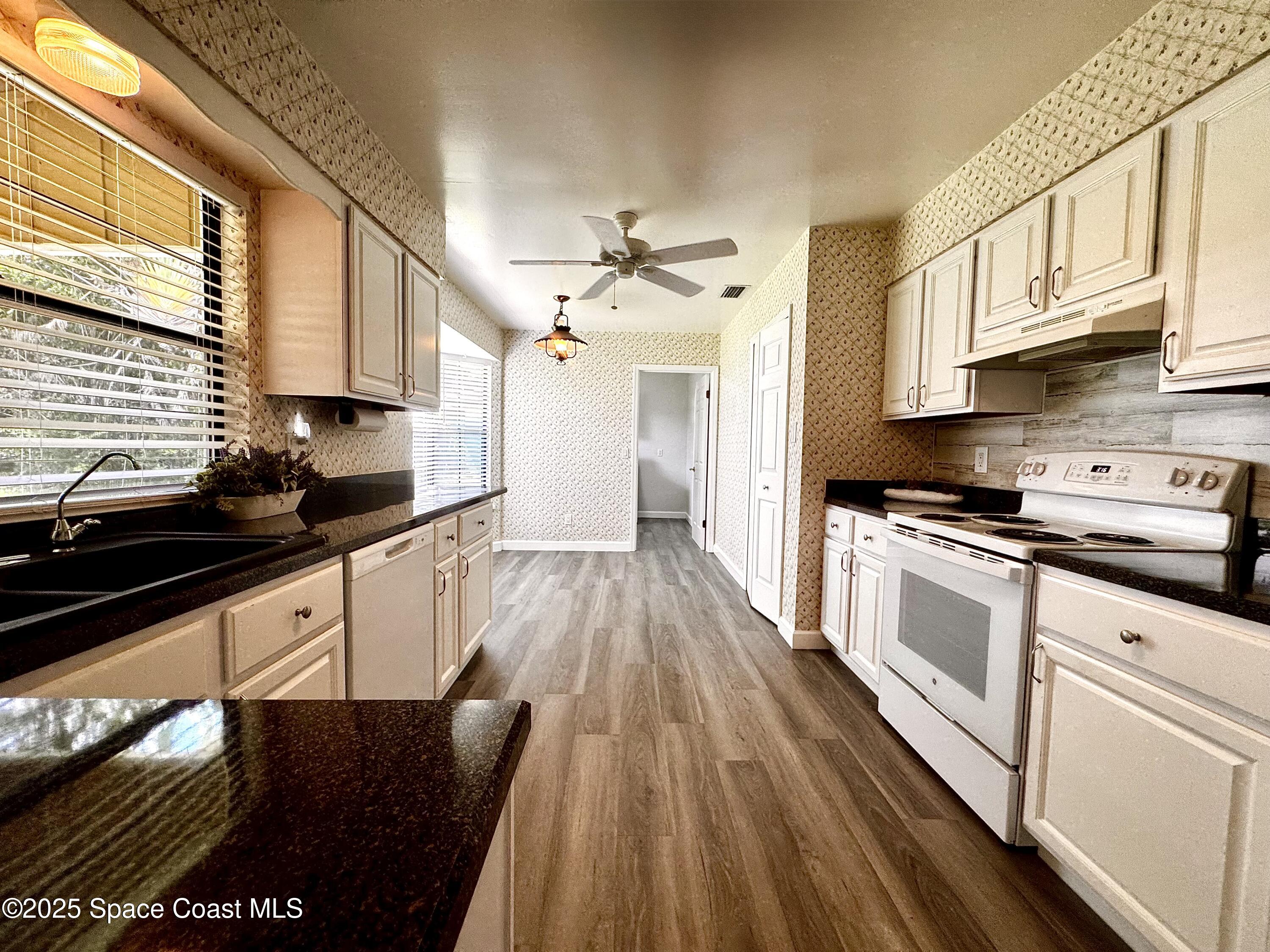 658 Ervin Street Sebastian, FL 32958 - Photo 17 of 36 a kitchen with granite countertop a stove a sink dishwasher and cabinets with wooden floor