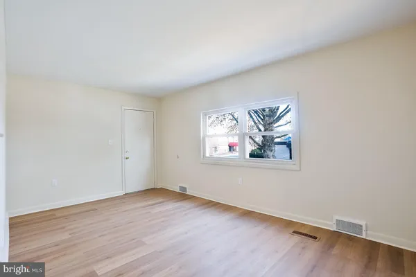 an empty room with wooden floor and window