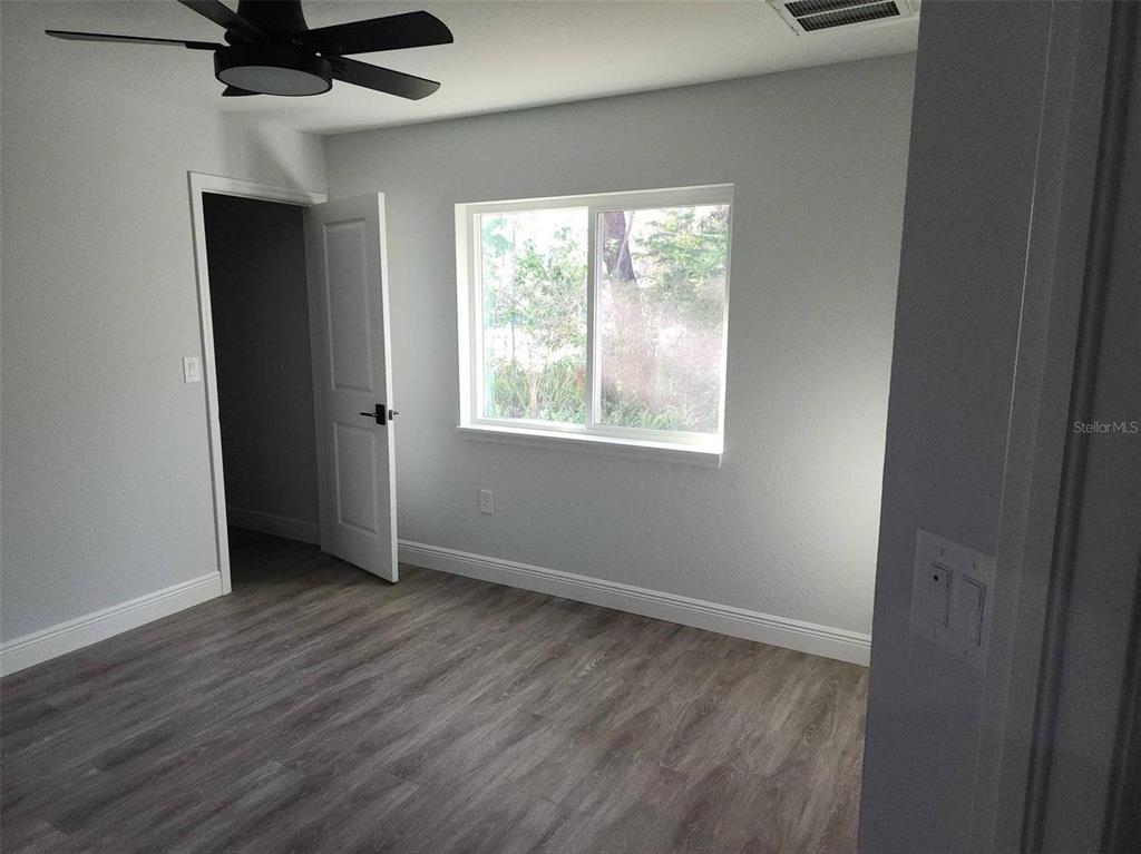 1111 Dagmar Avenue Spring Hill, FL 34606 - Photo 4 of 27 an empty room with wooden floor cabinet and windows
