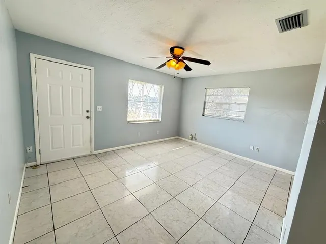 an empty room with windows and chandelier fan