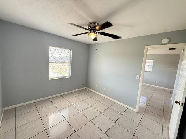 a view of an empty room with window and chandelier fan