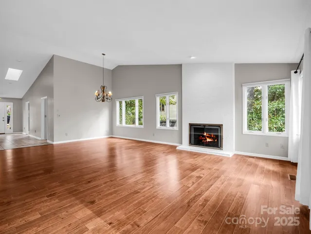 a view of an empty room with window and wooden floor