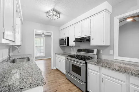 a kitchen with granite countertop a sink cabinets stainless steel appliances and a counter space
