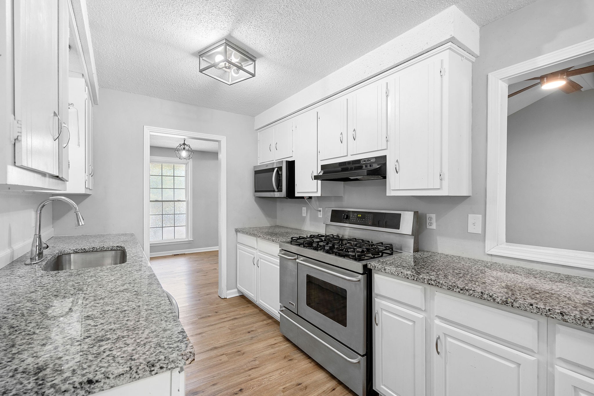 a kitchen with granite countertop a sink cabinets stainless steel appliances and a counter space
