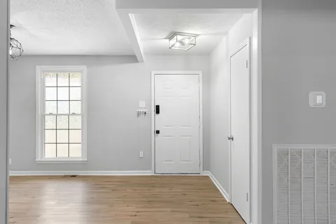 a view of an empty room with wooden floor and a window