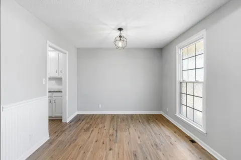 an empty room with wooden floor cabinet and windows