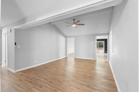 a view of an empty room with window and wooden floor