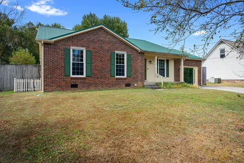 a front view of house with yard and trees in the background