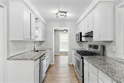 a kitchen with stainless steel appliances granite countertop a sink stove and cabinets
