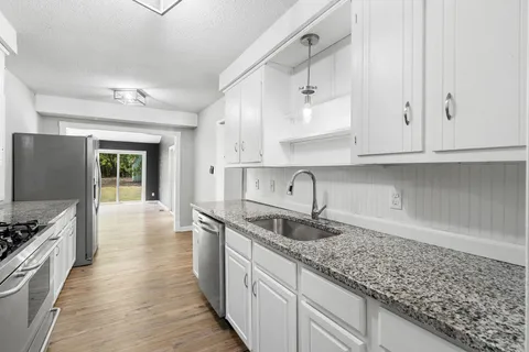 a kitchen with granite countertop a sink stove and cabinets
