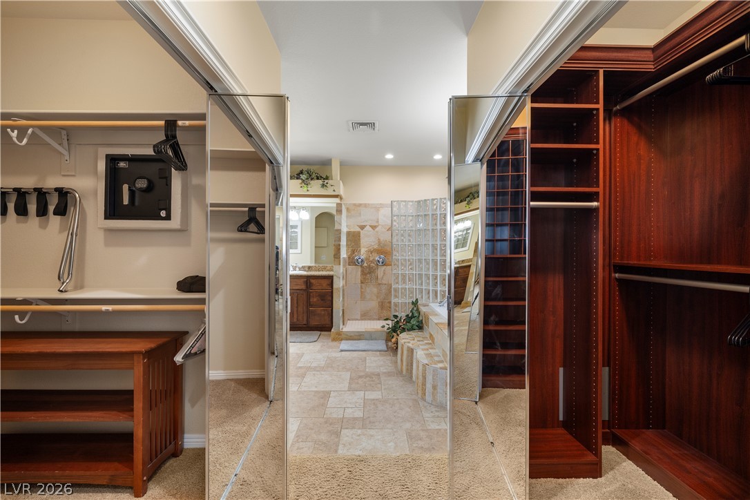2181 Winery Road Pahrump, NV 89048 - Photo 27 of 52 Custom closets with rich wood finishes frame the entrance to a spa like retreat primary bathroom.