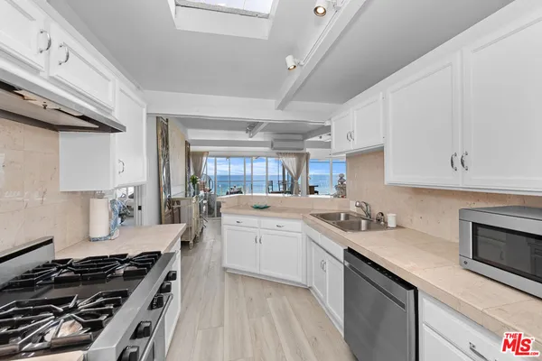 a kitchen with a stove a sink and wooden floor