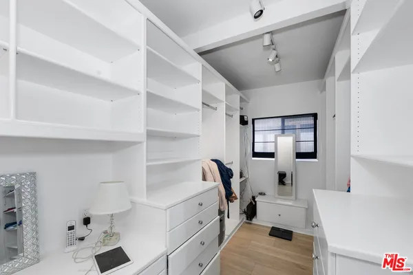 a view of walk in closet with clothes and shoes