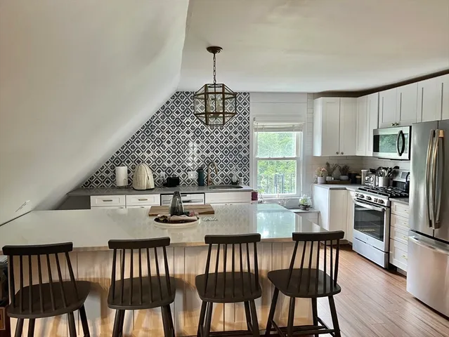 a kitchen with stainless steel appliances granite countertop a dining table chairs and granite counter tops