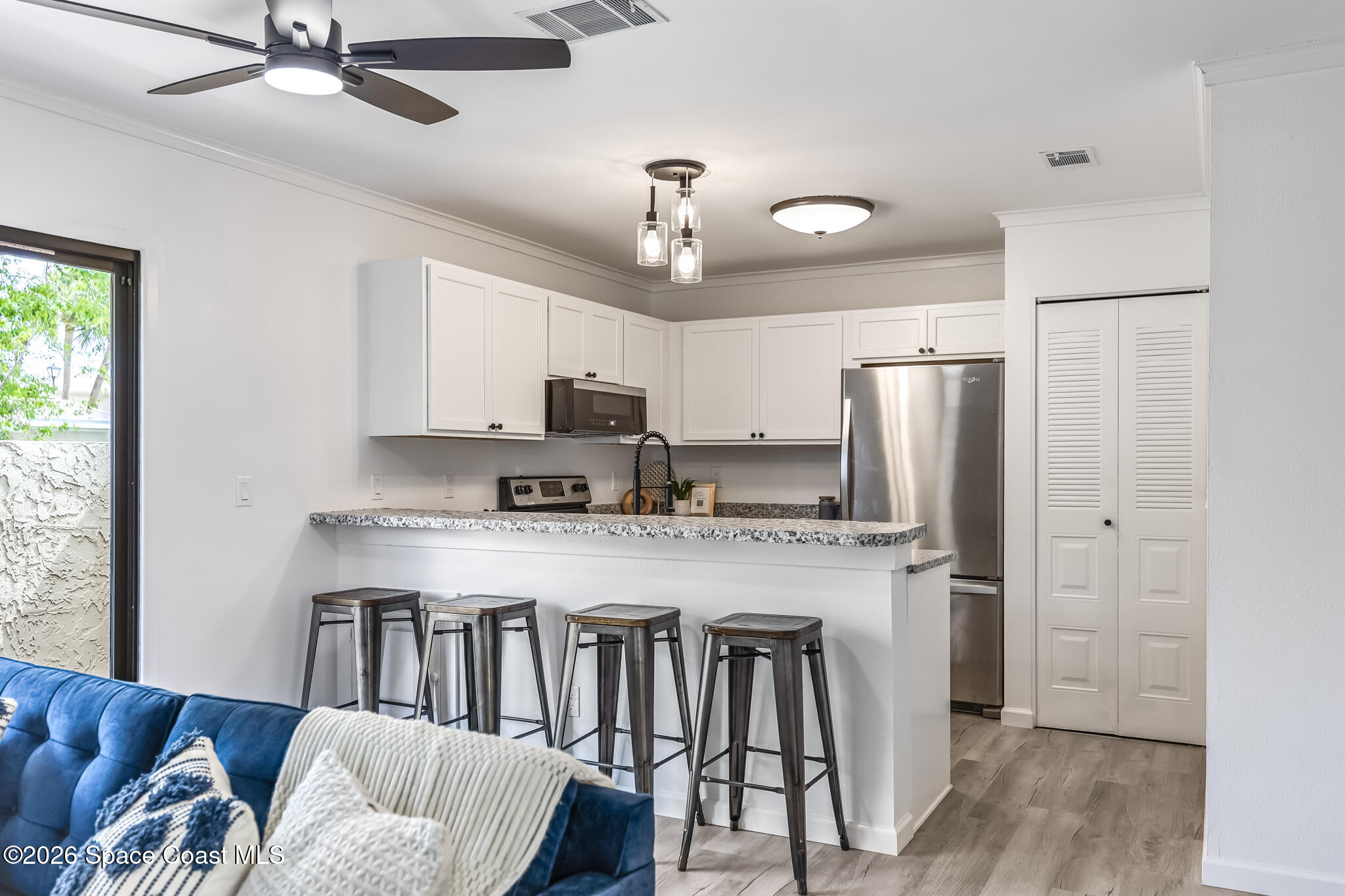1411 Sheafe Avenue Northeast, Unit 101 Palm Bay, FL 32905 - Photo 9 of 24 a kitchen with stainless steel appliances granite countertop a refrigerator a stove a sink dishwasher a dining table and chairs with wooden floor