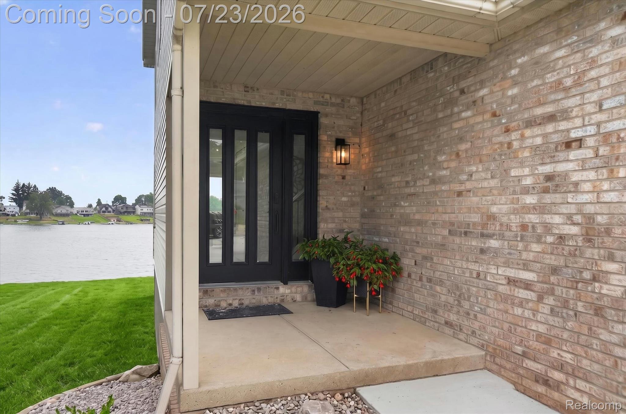 3429 Rolston Road Fenton, MI 48430 - Photo 45 of 62 Covered entry featuring a dark-paneled door with vertical glass inserts, an exterior wall light, and brick facade