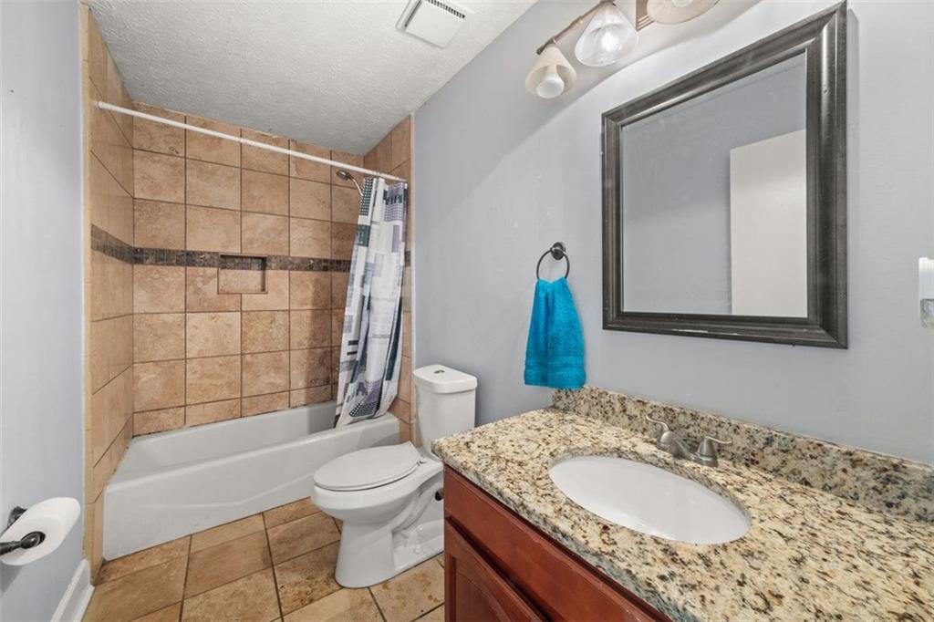 5016 Comanche Court Northwest Lilburn, GA 30047 - Photo 6 of 13 a bathroom with a granite countertop sink toilet a mirror and shower