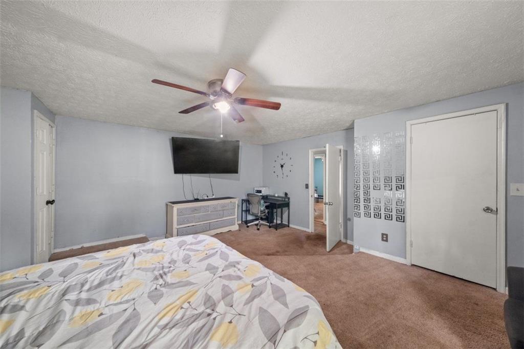 5016 Comanche Court Northwest Lilburn, GA 30047 - Photo 9 of 13 a bedroom with a bed and a flat tv screen on wall