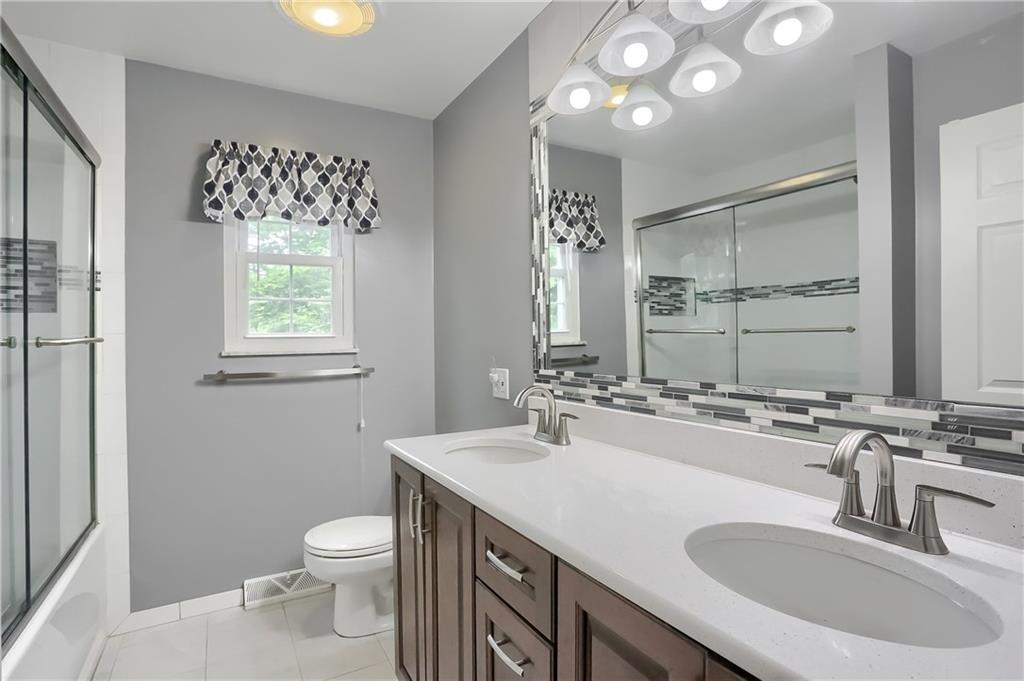 233 Foxglove Road Baden, PA 15005 - Photo 20 of 25 The shared hall bath is updated and features a tub/shower combo with glass door. Quartz counter tops are enhanced by the custom back splash, modern lighting and custom vanity.