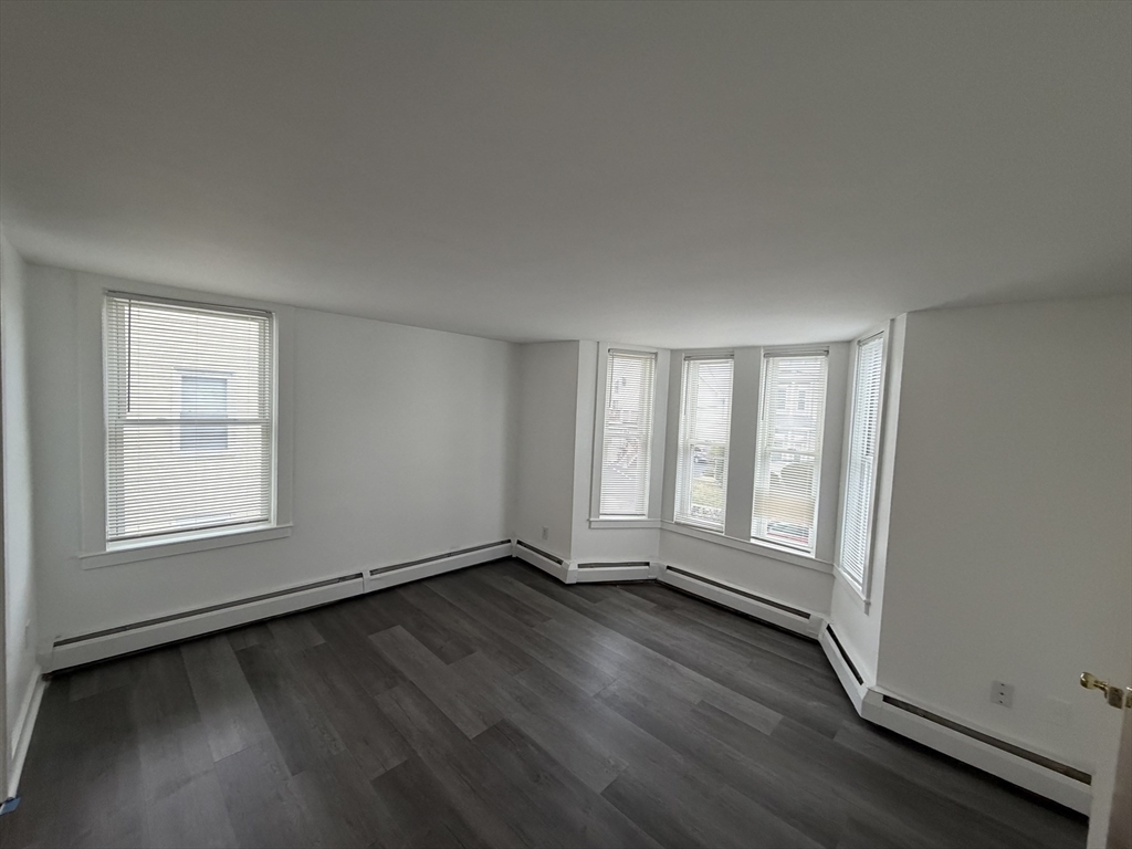 149 Adams Street, Unit 149 Waltham, MA 02453 - Photo 2 of 12 an empty room with wooden floor and windows