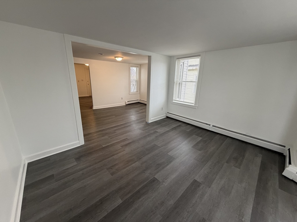 149 Adams Street, Unit 149 Waltham, MA 02453 - Photo 3 of 12 a view of an empty room with wooden floor and a window