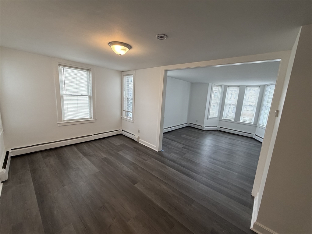 149 Adams Street, Unit 149 Waltham, MA 02453 - Photo 4 of 12 an empty room with wooden floor and windows