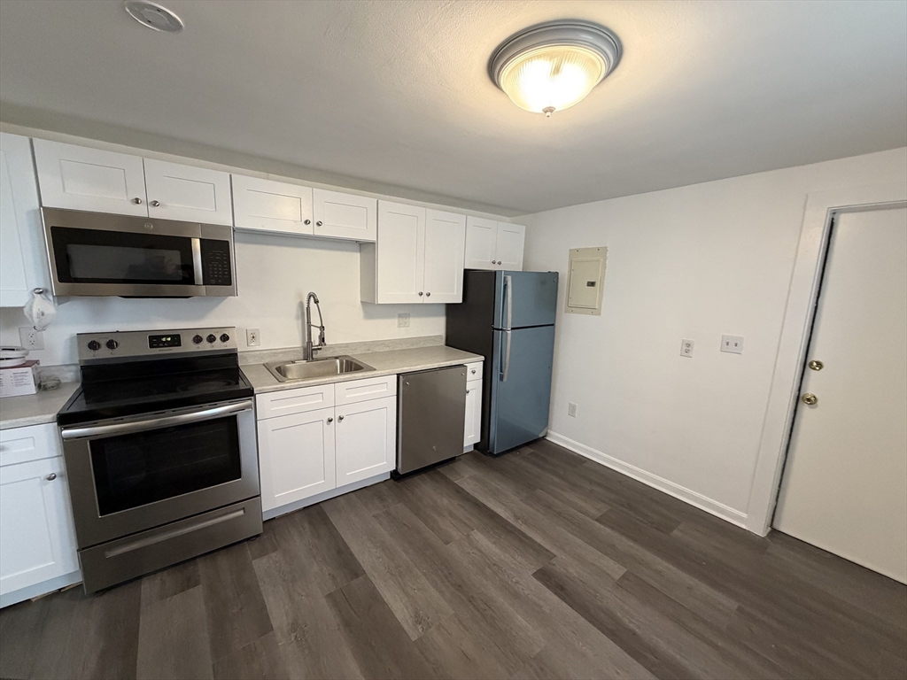 149 Adams Street, Unit 149 Waltham, MA 02453 - Photo 6 of 12 a kitchen with a sink a microwave a refrigerator and cabinets