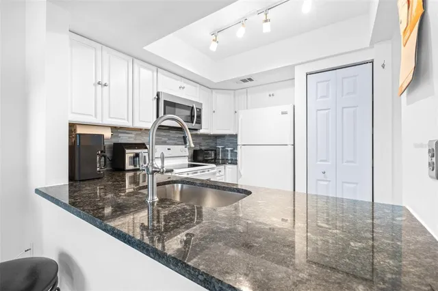 a kitchen with stainless steel appliances granite countertop a refrigerator a stove and a sink