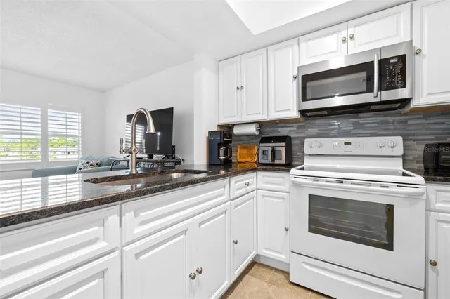 a kitchen with cabinets stainless steel appliances a sink and a window