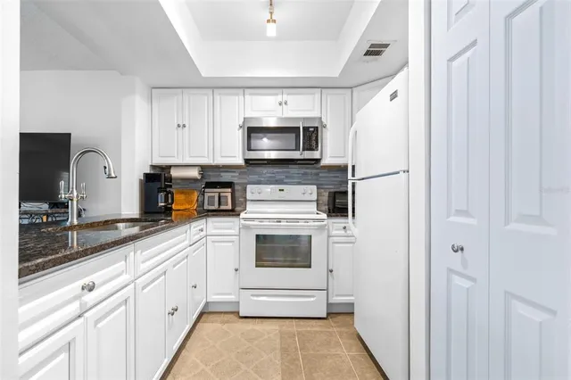 a kitchen with white cabinets and stainless steel appliances