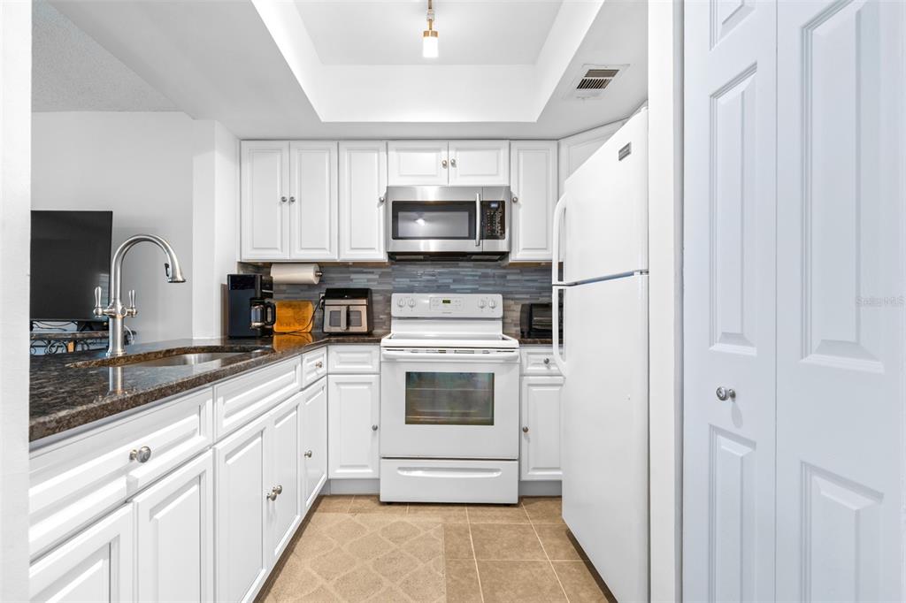 1250 South Pinellas Avenue, Unit 711 Tarpon Springs, FL 34689 - Photo 13 of 33 a kitchen with white cabinets and stainless steel appliances