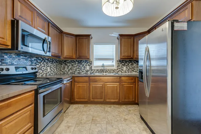 a kitchen with stainless steel appliances granite countertop a sink stove and refrigerator