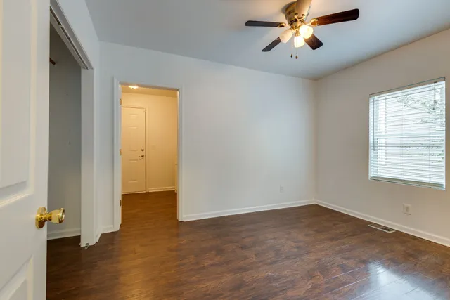 a view of empty room with wooden floor and fan