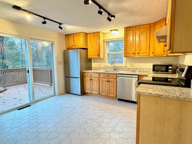 a kitchen with stainless steel appliances granite countertop a stove a sink dishwasher a refrigerator and cabinets with wooden floor