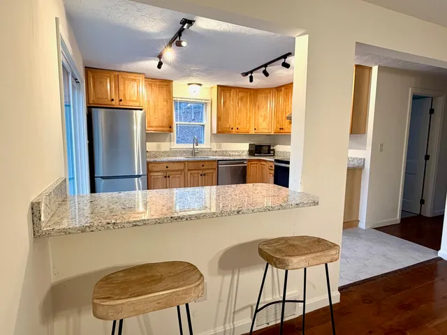 a kitchen with stainless steel appliances granite countertop a sink and a refrigerator