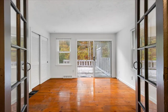 a view of an empty room with window and wooden floor